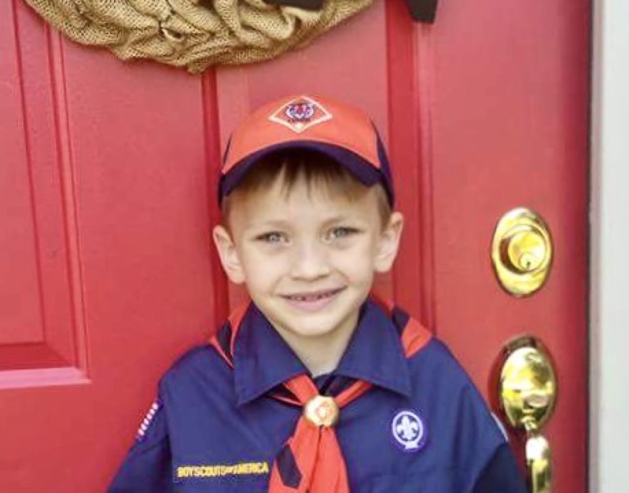 Quinn as a young Cub Scout in uniform, smiling on the front porch.