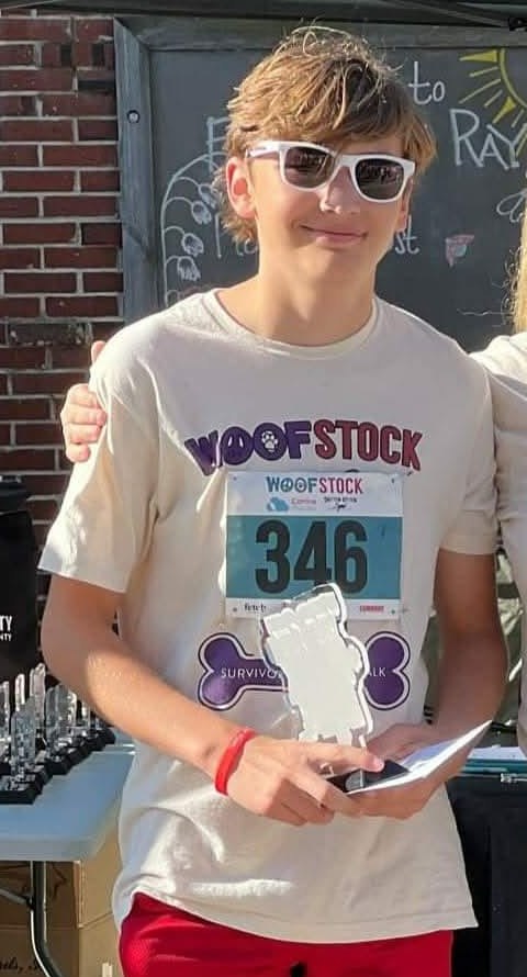 Quinn holding a trophy after being named Top Youth Fundraiser at a Humane Society dog walk.